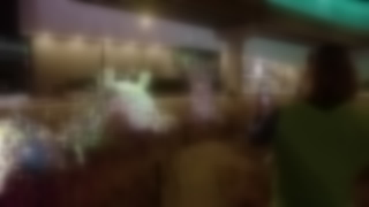 Heavily blurred, redacted still of a dim environment with glowing teal and amber shapes, details obscured under NDA